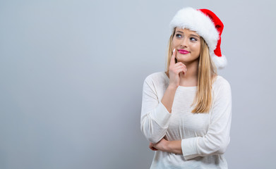 Young woman with Santa hat thoughtful pose on a gray background