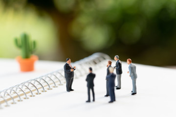 Miniature people meeting on a NoteBook . meeting or Discussion using as background business concept with copy space and white space for your text or  design.