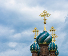 Fototapeta na wymiar Beautiful church domes with gold crosses against a cloudy sky.