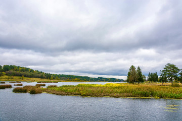 Autumn landscape with a river and a cloudy sky on an overcast day.