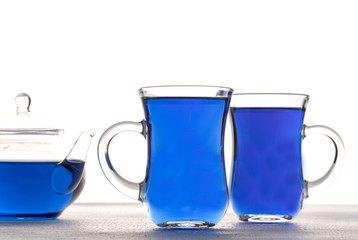 Cup and teapot of butterfly pea tea isolated on white background