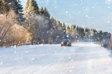 The car is driving on a winter road in a blizzard