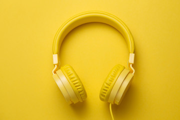 Yellow headphones on yellow background. Music concept.