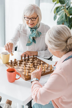 senior women playing chess and drinking coffee in nursing home