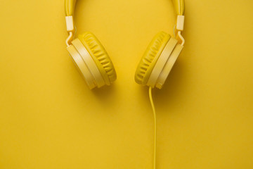 Yellow headphones on yellow background. Music concept.