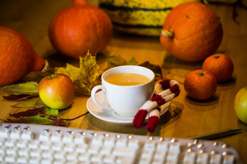 Coffee cup with keyboard, in the background pumpkin, leaves, pumpkin