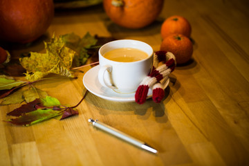 Coffee cup with pen, in the background pumpkin, leaves, apples