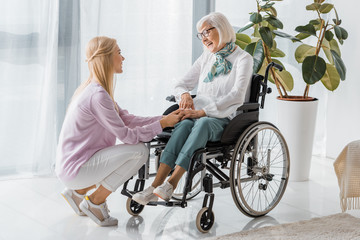 young woman speaking with senior woman in wheelchair at nursing home