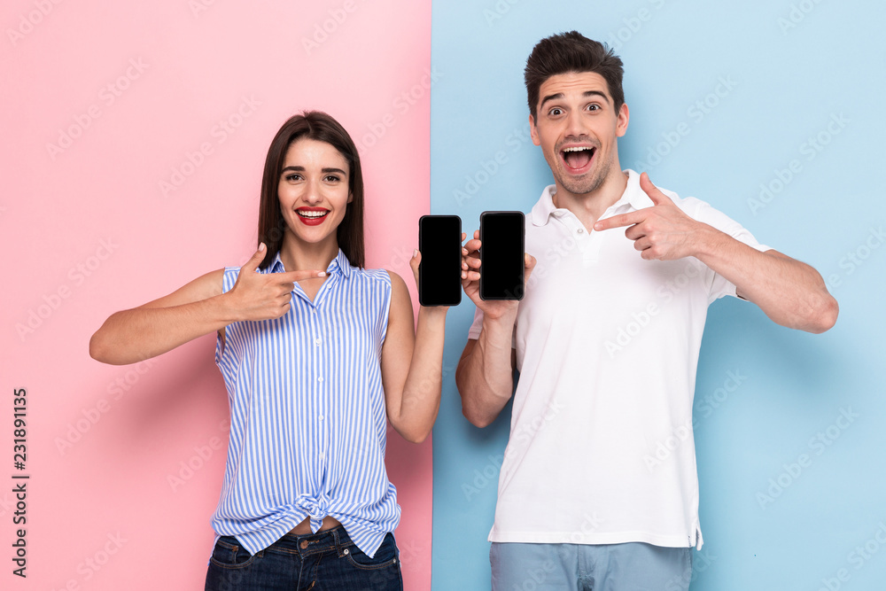 Sticker Image of smiling man and woman in casual wear standing and holding cell phones, isolated over colorful background