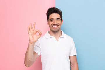 Naklejka premium Image of man 30s having stubble showing ok sign with happy smile, isolated over colorful background