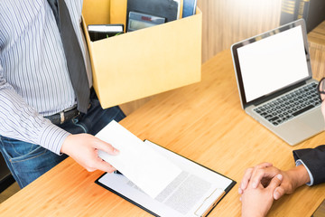 Hand of a businessman hands over a resignation letter final remuneration to executive boss on a wooden table to his boss Change of job, unemployment concept