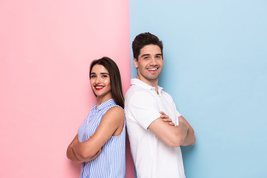 Image of european man and woman in casual wear standing back to back with arms crossed, isolated over colorful background