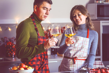 Couple celebrating Christmas in the kitchen and drink wine