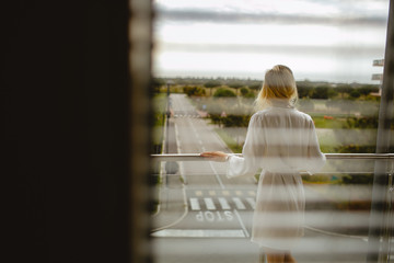 Back view of young girl dressed in bathrobe on balcony. Park outdoor background.
