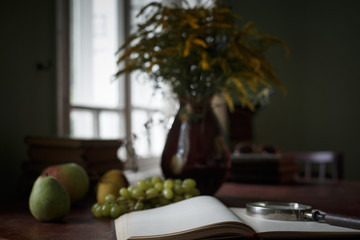 Old books on a wooden table and glass magnifier.