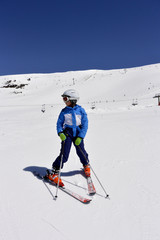 A boy in ski suit, helmet and sunglasses skiing from snowy mountains in Serra Nevada