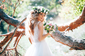 beautiful bride in nature in a coniferous forest in a wreath on her head and a luxurious wedding...