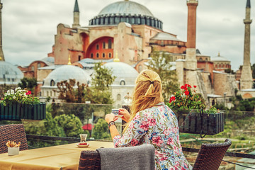 Girl drinks Turkish coffee enjoying the view of the Hagia Sophia Museum.