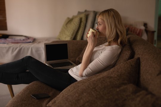 Woman having coffee in living room at home