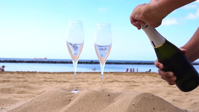 someones hands opening bottle of champagne and pouring drink into the glasses