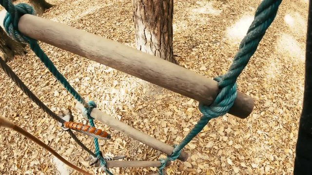 Person POV climbing on tree with rope ladder in adventure park 4K. Camera on a person's head with a wide view while climbing in adventure park in autumn. Slow motion first person view.