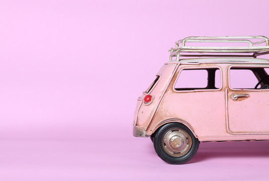 Pink miniature car on pink background, insurance concept