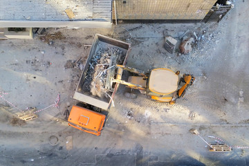 Bulldozer loader uploading waste and debris into dump truck at construction site. building...