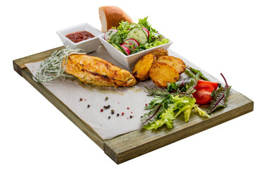 Set of baked chicken fillet, vegetable salad, potatoes and sauce. On a wooden board.
