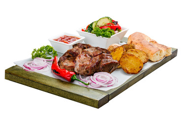 Pork shish kebab with vegetable salad, potatoes and sauce. On a wooden board.