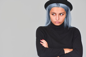 Horizontal portrait of beautiful young teenager woman with blue hair looking at one side, with serious expression. Grumpy young female with dissatisfied expression. Copy space. People, lifestyle