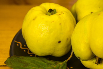 large yellow quince fruits on a ceramic plate, with anise, cinnamon, and walnuts