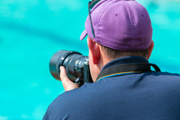 Male photographer taking picture with his camera at a swimming pool