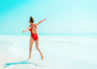 Fototapeta na wymiar young woman in red swimsuit on seacoast having fun time