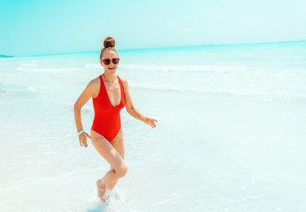 happy young woman in red swimwear on beach running