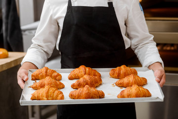 Baker presenting freshly baked croissants