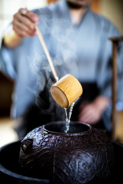 Close up of traditional Japanese Tea Ceremony, man using a Hishaku, a bamboo ladle, to pour hot water.