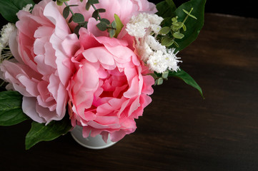 Pink artificial peonies on a black background.