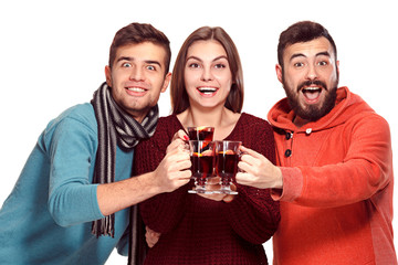 Smiling european men and women during party photoshoot. The guys posing as friends at studio fest with wineglasses with hot mulled wine on foreground.