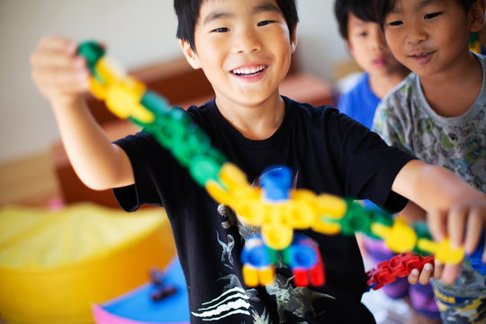 Close up of smiling boy holding colourful toy in a Japanese preschool.