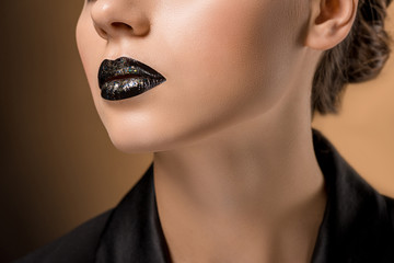 close up of young beautiful woman with glittery black lips