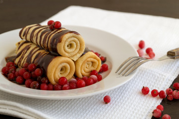 Homemade pancakes twisted with chocolate on a white plate.