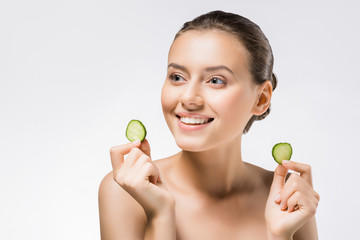 young smiling woman holding cucumber slices