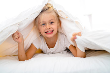 A Cheerful little girl in bed having fun