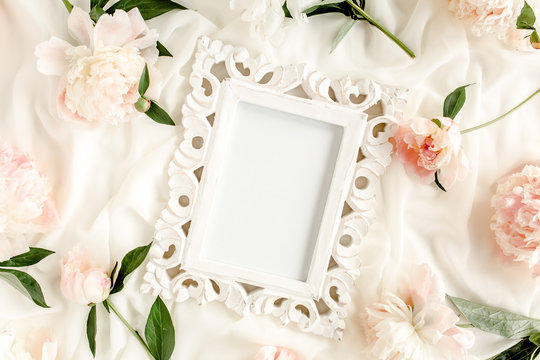 Carved, white frame decorated of beautiful pink peonies on white background. Flat lay, top view. Valentine's background. Floral frame. Peony texture.