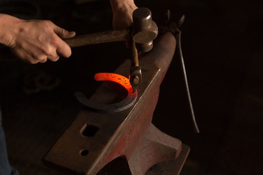 Female metalsmith molding horseshoe in factory