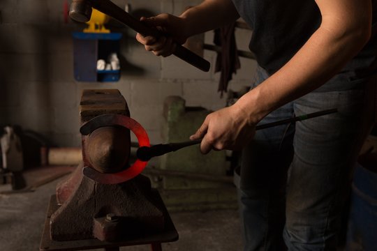 Female metalsmith molding horseshoe in factory