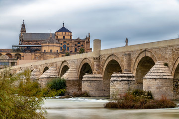 Obraz premium Long exposure photography of Mosque-Cathedral and the Roman Bridge in Cordoba with cloudy sky, Andalusia, Spain