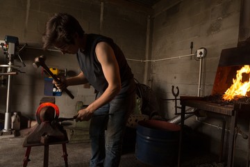 Female metalsmith molding horseshoe in factory