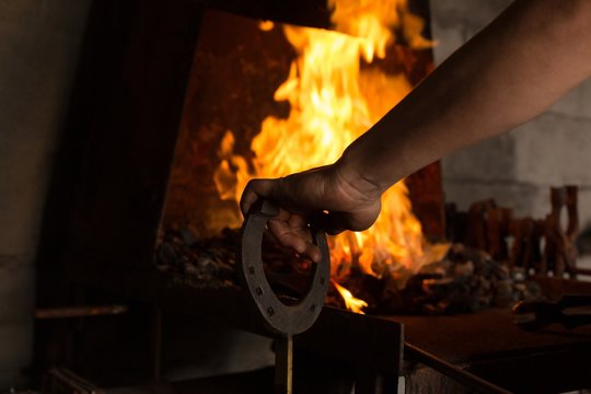 Female mtalsmith heating horseshoe in fire
