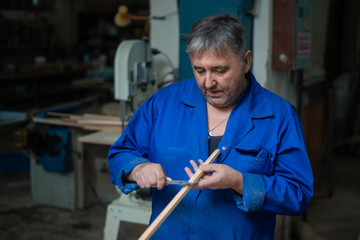 Carpenter at work in workshop, a man makes measurements